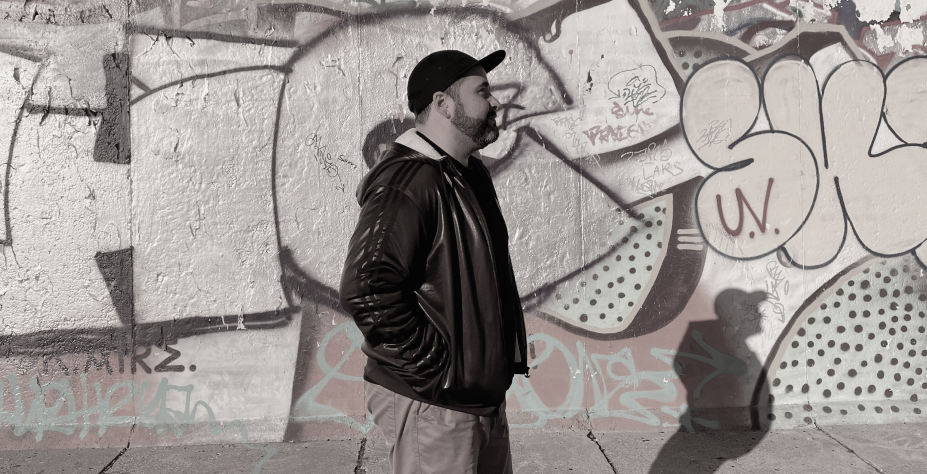 Victor Tademos standing in front of a graffiti wall